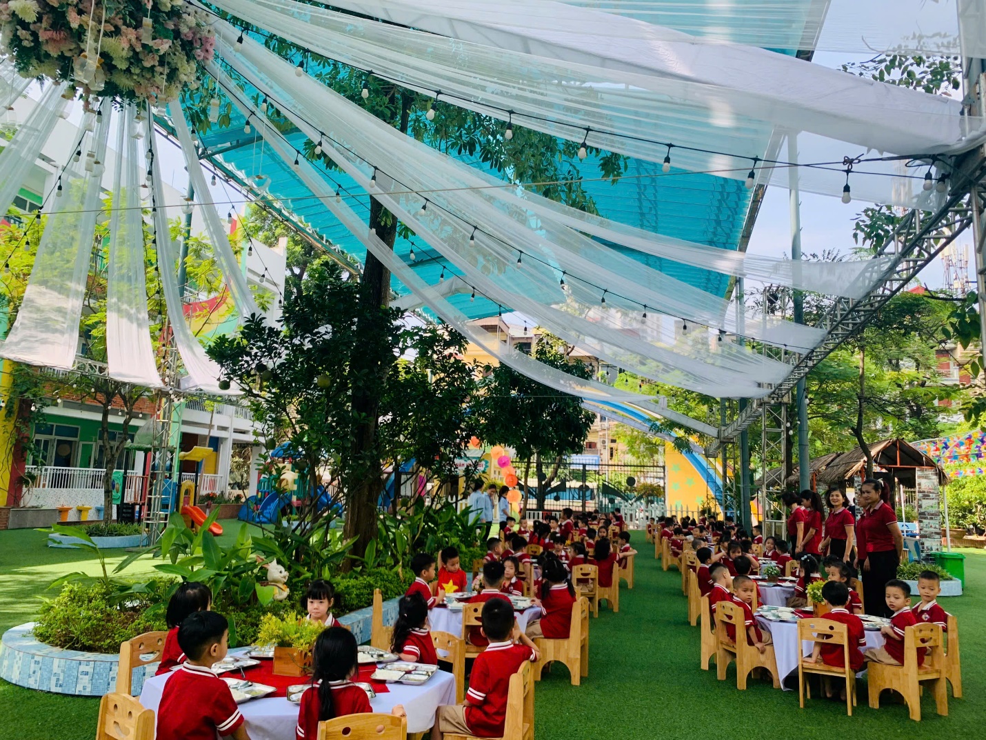 A group of children sitting at tables in a courtyard with Mall of America in the background

Description automatically generated