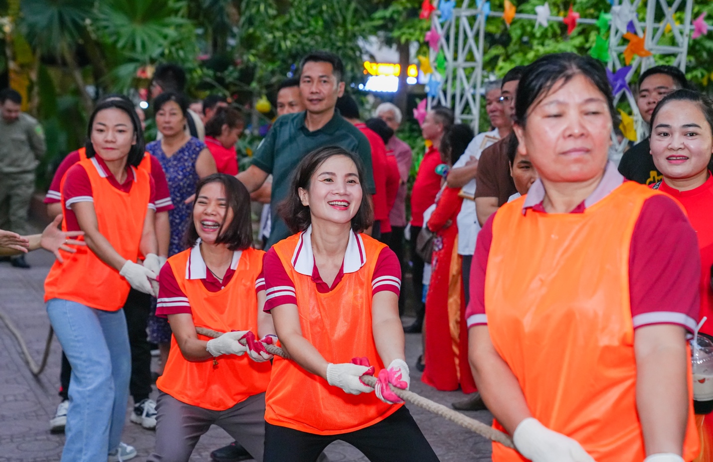 A group of people in orange vests pulling a rope

Description automatically generated