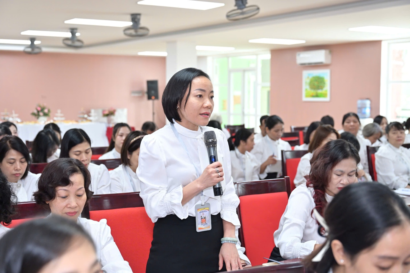 A person holding a microphone in front of a group of people

AI-generated content may be incorrect.