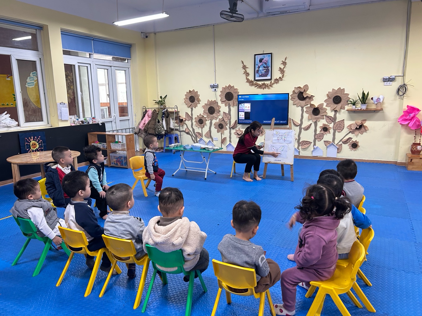 A group of children sitting in chairs in a room with a person teaching a lesson

AI-generated content may be incorrect.