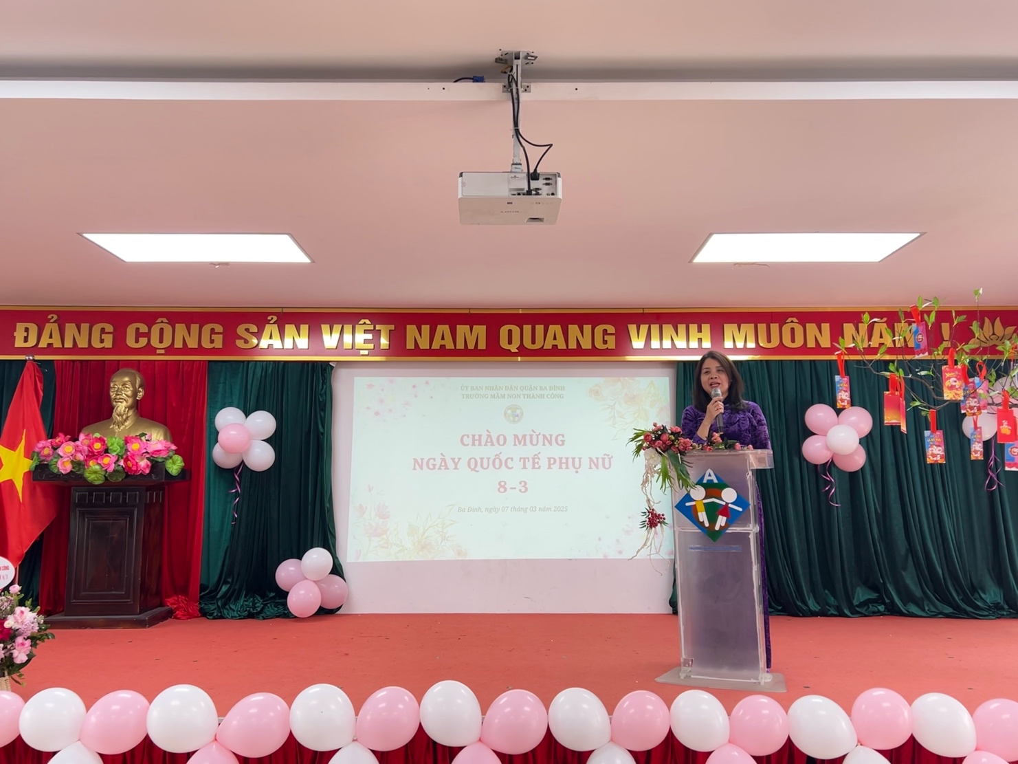 A person standing at a podium with a podium and balloons

AI-generated content may be incorrect.